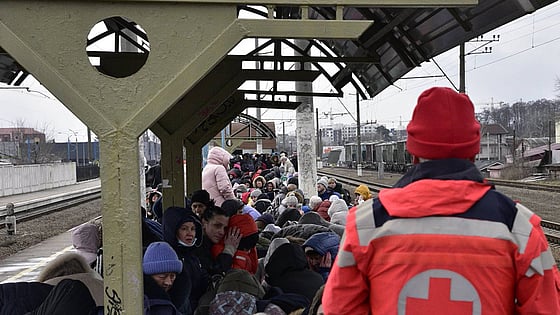 Röda korset volontär och flyktingar på en tågstation i Ukraina.