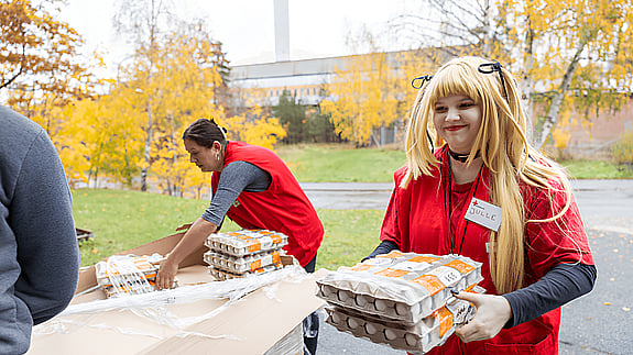 Volontär bär en låda med ägg - packar ur en bil