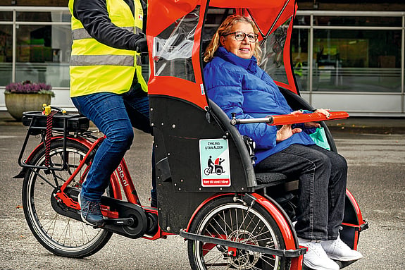 En volontär från Röda Korset kör en kvinna i en lådcykel.
